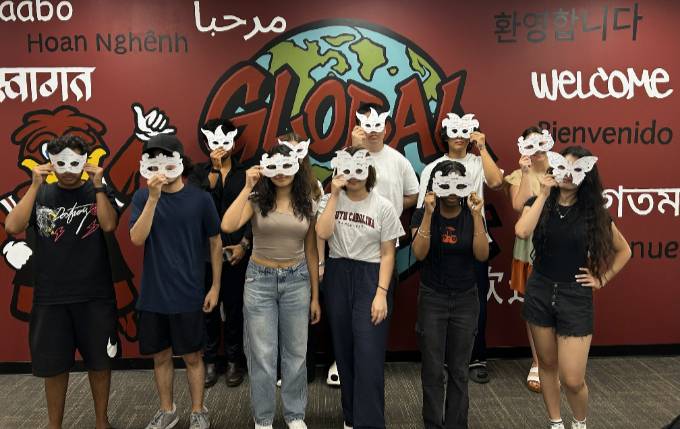 Ten students standing next to each other holding up masks from an activity.