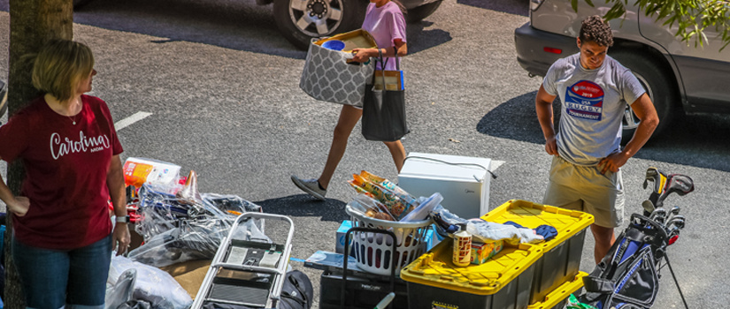 Mother and son looking over packed items on the side of a street during move in