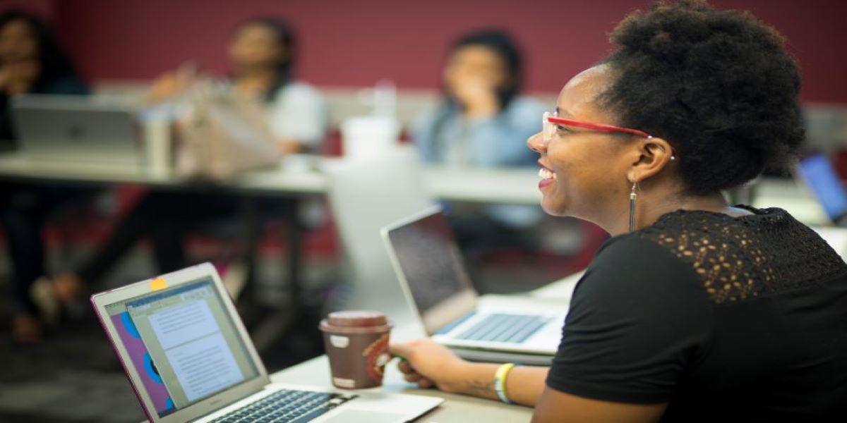 Female sitting in front of her laptop smiling. 