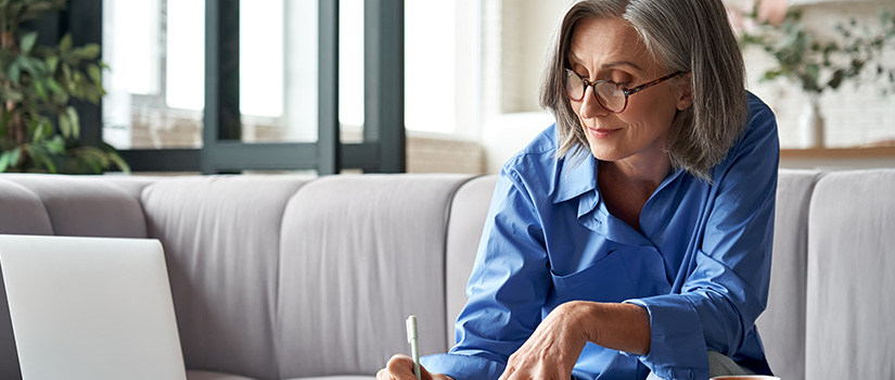 Woman writing and working near a laptop