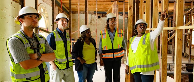 individuals in hard hats looking at a building project