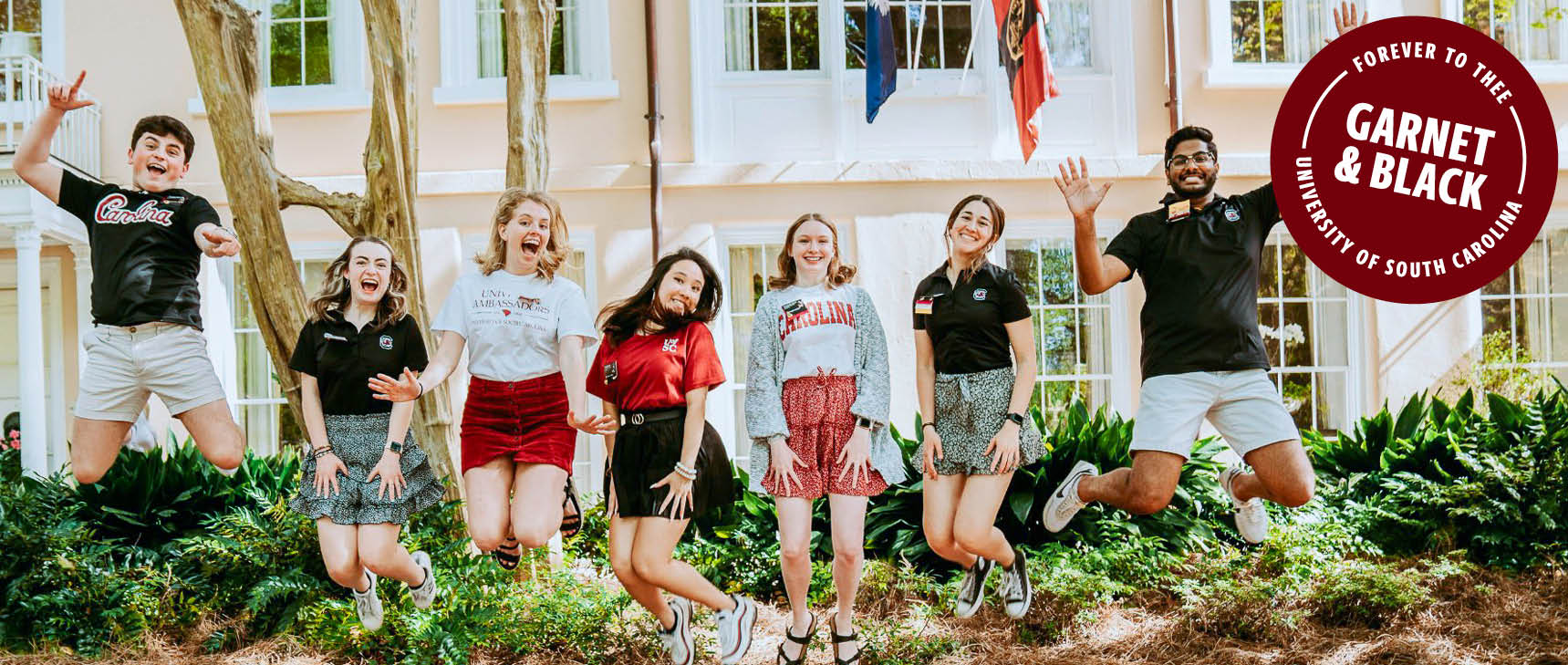 Student ambassadors jumping on the horseshoe with an overlaid stamp stating forever to thee garnet and black University of South Carolina 