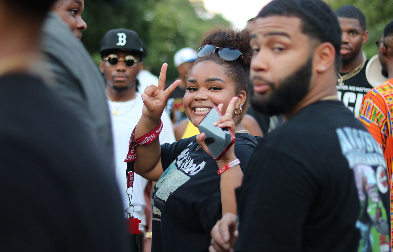 Student smiling at the camera holding up peace signs. 