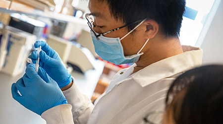 Researcher holding a test tube in a lab. 