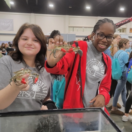 Middle school students holding blue crabs