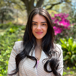 woman with dark long hair smiling outside 