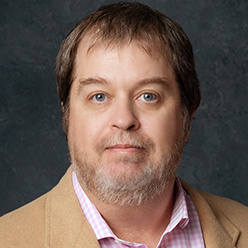 man in tan jacket with brown hair