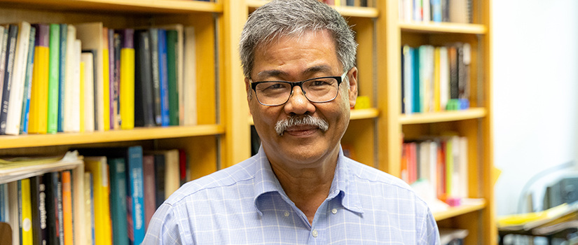 man with glasses standing in front of books