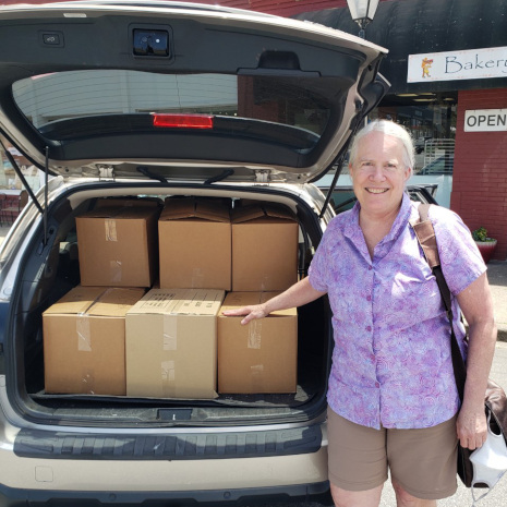 Pamela Mack standing besides a car with truck open and books inside