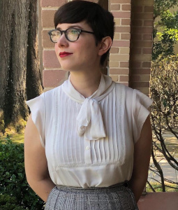 Jenna wears a white blouse and plaid skirt and looks away from the camera