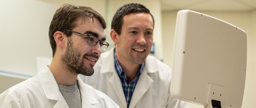 a graduate student looks at a screen with Dr. Gower