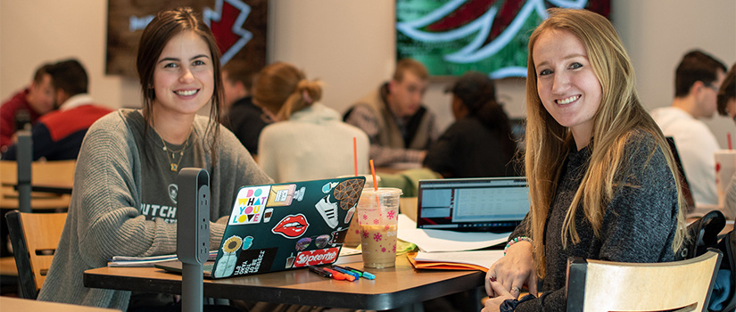 two female students sitting at a table in the cafe