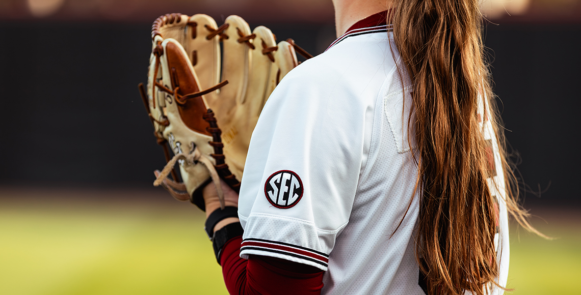 Softball player holding her mitt close with 'SEC' embroidered on her uniform.