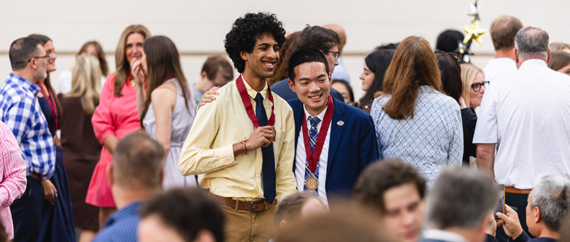 Two students posing for a picture with their Honors medallions.