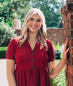 Courtney Tkacs posing on the USC's Historic Horseshoe with her hand resting on a brick wall.