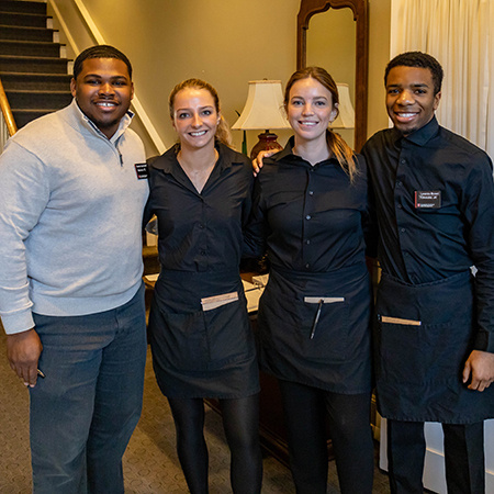 Four student workers pose for a photo together inside McCutchen House.