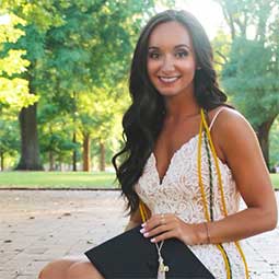 Erica DeVito on the Horseshoe with her cap, cords and gown