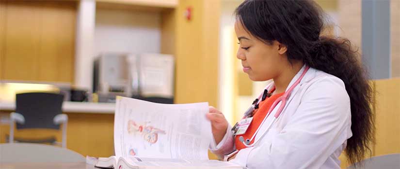 Female med student turns the pages of an anatomy book.