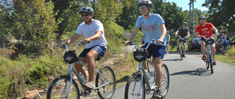 A group of cyclists ride on a paved path.