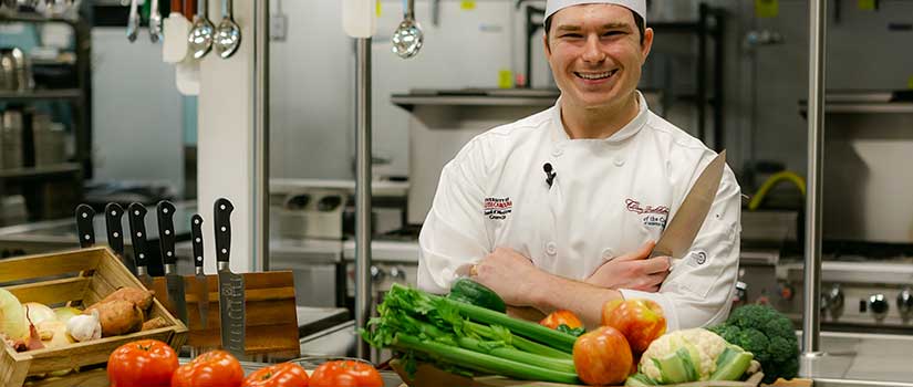 UofSC School of Medicine Greenville culinary medicine chef behind stacks of fresh veggies.