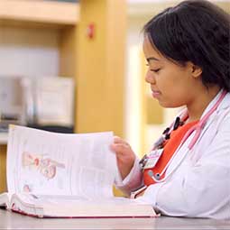 Female med school student reads an anatomy book.