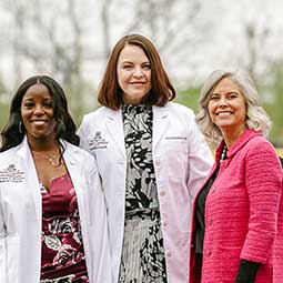 Med student poses on stage with the dean and donor.