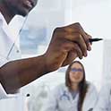 Med student in white coat writes formula on clear glass