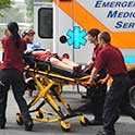 Student EMTs load a patient on a stretcher into an ambulance.