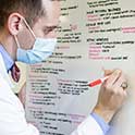 Med student in mask writes on whiteboard