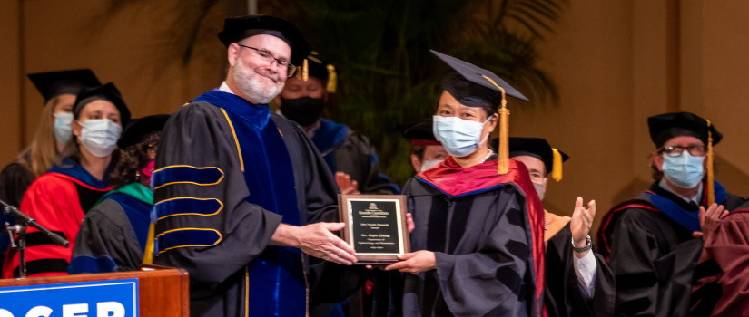 A professor accepting an excellence in teaching award from the dean