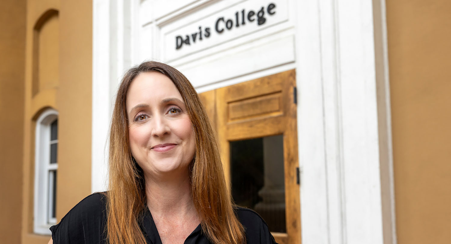 Jennifer Moore (woman) stands in front of Davis College on USC campus