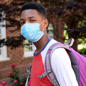 student wearing mask, red shirt with backpack