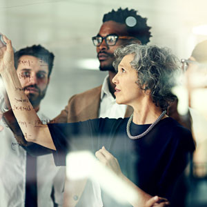 Group of people writing ideas on a window inside of an office