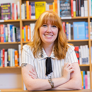 Ashley Poston sits at table in front of bookshelves