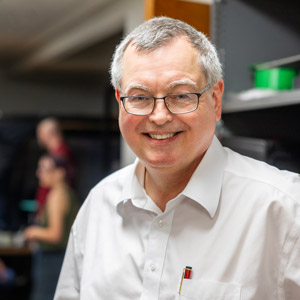 A man stands in a room with people in the background