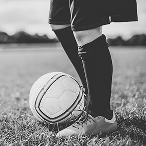 A kid with soccer gear on with a soccer ball at their feet. 