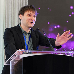 man gestures while talking from a podium