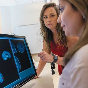 Two workers view brain scans in the C-STAR lab.