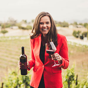 Kellie Martin holding a bottle of wine and a glass of wine.