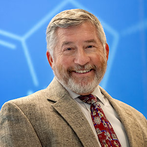 Head and sholders photo of man in front of blue background